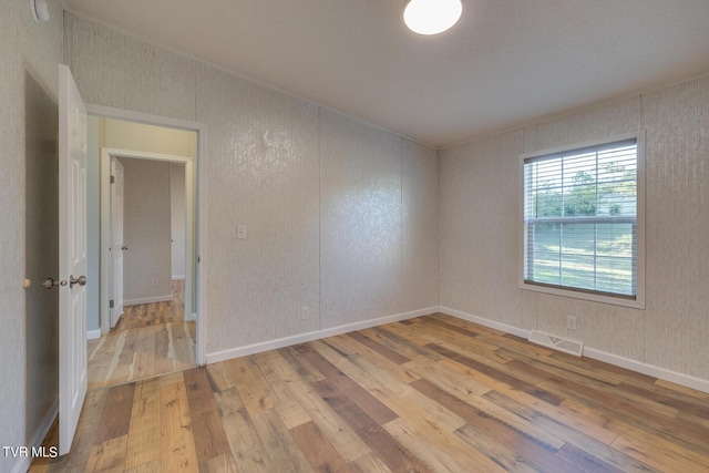 unfurnished room with baseboards, visible vents, and hardwood / wood-style flooring