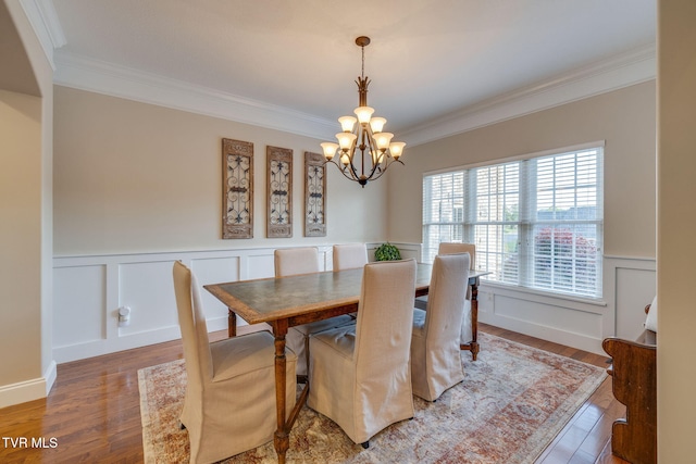 dining space featuring ornamental molding, light wood-style flooring, wainscoting, and a chandelier