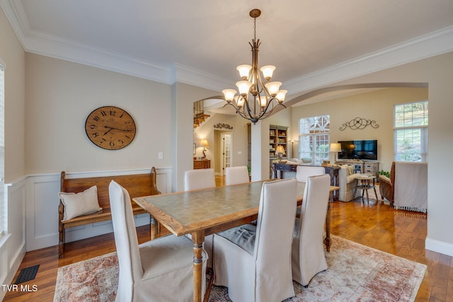dining space featuring visible vents, crown molding, arched walkways, a chandelier, and light wood-style flooring