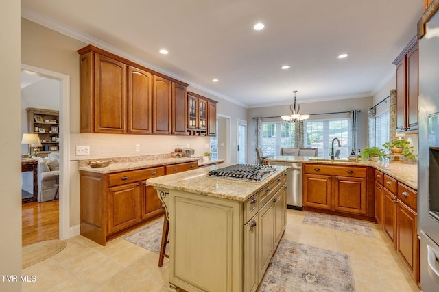 kitchen with a sink, light stone counters, ornamental molding, and stainless steel appliances