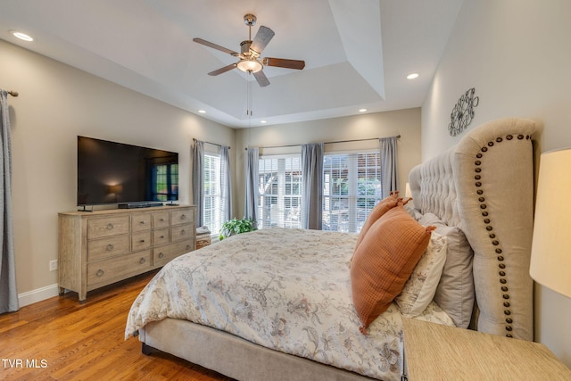 bedroom featuring ceiling fan, a raised ceiling, recessed lighting, baseboards, and wood finished floors