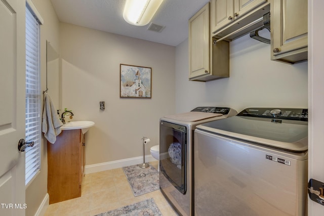 laundry area with visible vents, light tile patterned flooring, baseboards, washer and clothes dryer, and a sink