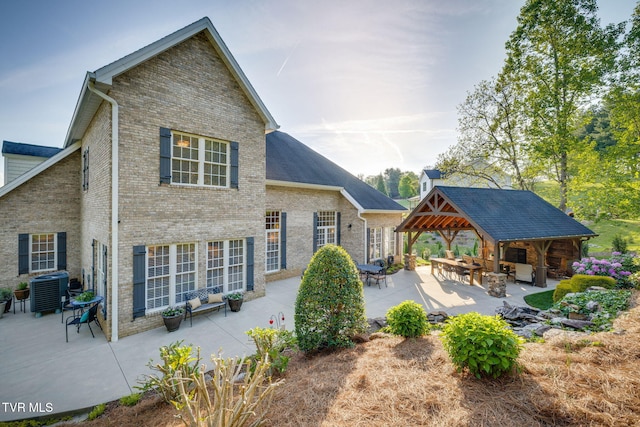 rear view of house with outdoor dry bar, a gazebo, central AC, brick siding, and a patio area