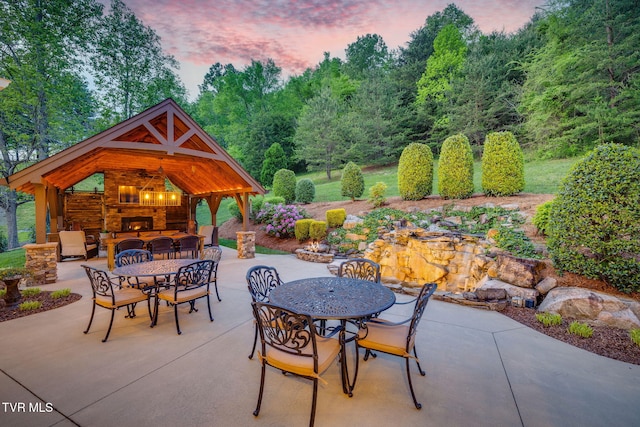 view of patio / terrace featuring an outdoor stone fireplace, a gazebo, and outdoor dining area
