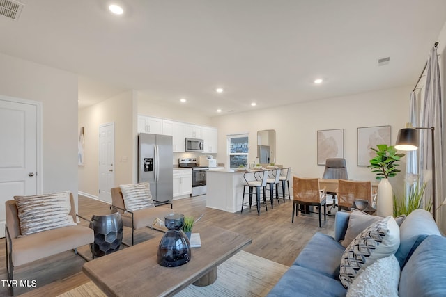 living area featuring visible vents, recessed lighting, and light wood-style floors