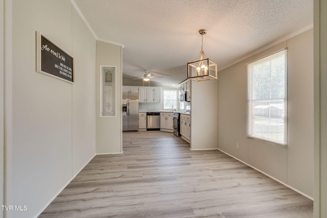 unfurnished dining area featuring crown molding, a textured ceiling, ceiling fan with notable chandelier, and light wood-style floors