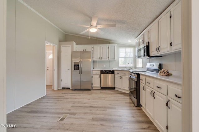 kitchen featuring ceiling fan, a textured ceiling, appliances with stainless steel finishes, vaulted ceiling, and light countertops