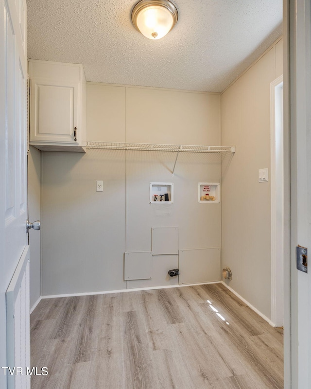 laundry area featuring cabinet space, washer hookup, a textured ceiling, baseboards, and light wood-type flooring