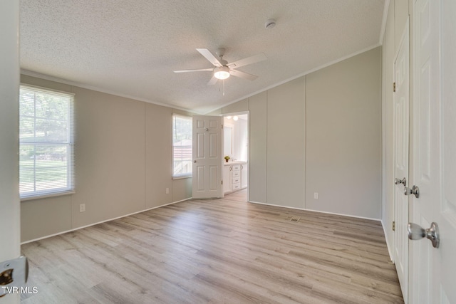 unfurnished bedroom with crown molding, light wood-style floors, vaulted ceiling, and a textured ceiling