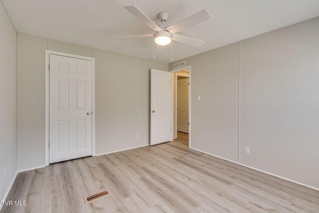 unfurnished bedroom with a textured ceiling, wood finished floors, and visible vents