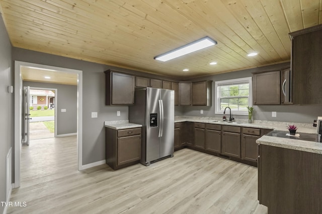 kitchen featuring dark brown cabinets, appliances with stainless steel finishes, a sink, light wood finished floors, and wood ceiling