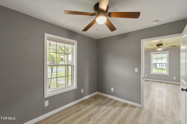 unfurnished room featuring baseboards, ceiling fan, a wealth of natural light, and light wood-style flooring