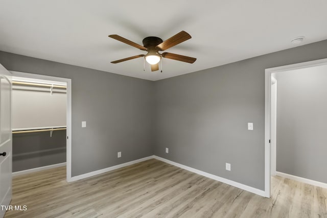 unfurnished bedroom featuring baseboards, a walk in closet, wood finished floors, and a closet