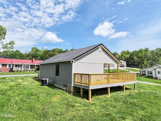 exterior space with central air condition unit, a deck, metal roof, and a lawn
