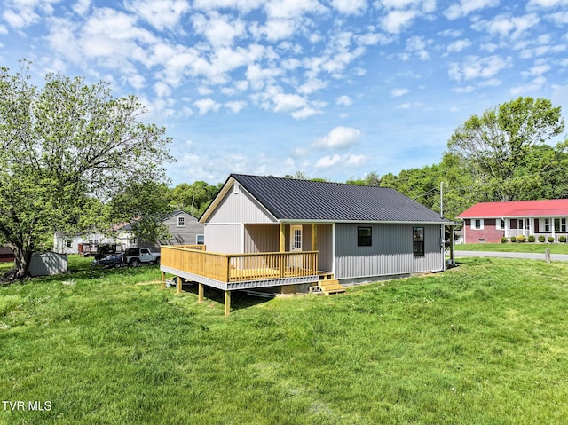 rear view of house with a wooden deck, a yard, and metal roof