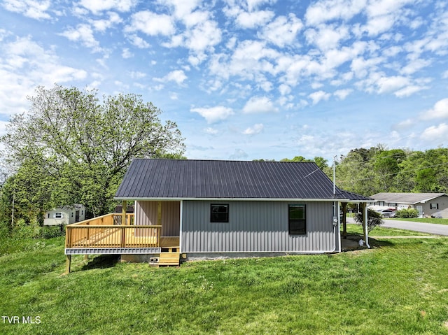 back of property with a deck, a yard, and metal roof