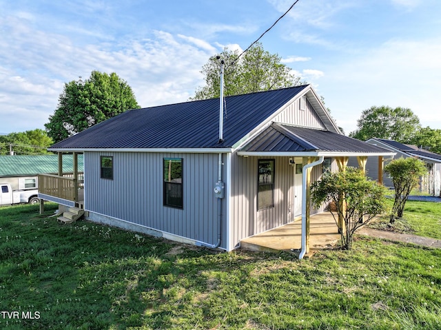 view of front of property featuring covered porch, metal roof, and a front lawn