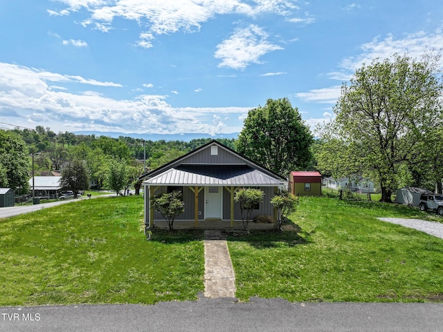 bungalow-style home with a storage unit, covered porch, an outdoor structure, and a front yard