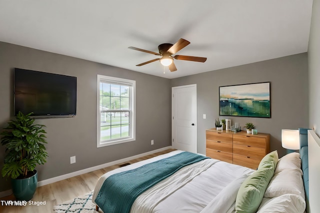 bedroom featuring baseboards, ceiling fan, and light wood-style flooring