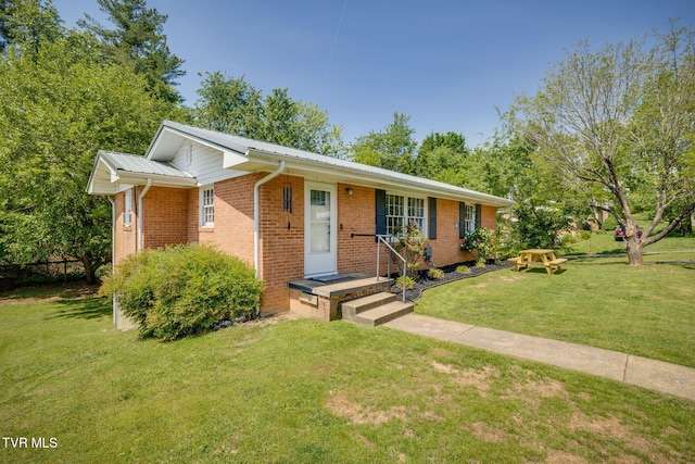 view of front of house featuring brick siding, a front yard, and metal roof
