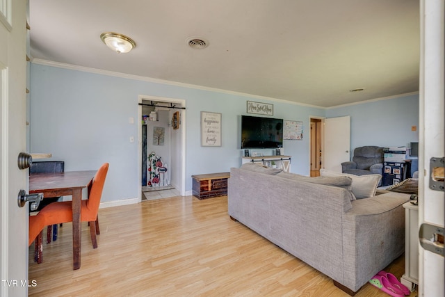living room featuring ornamental molding, light wood-style flooring, and visible vents