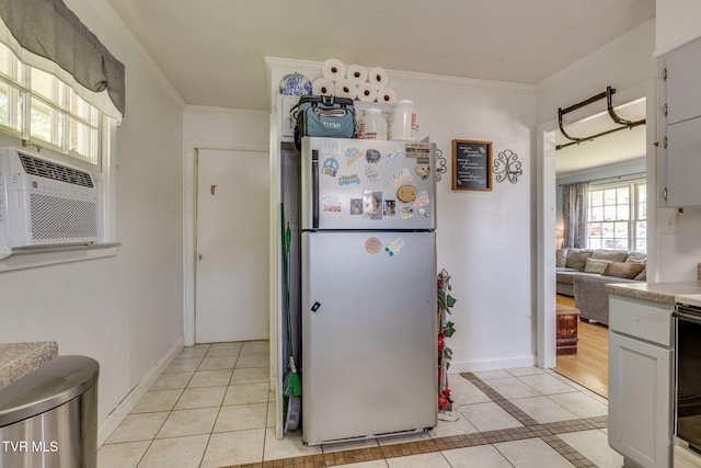 kitchen featuring light tile patterned floors, light countertops, crown molding, and freestanding refrigerator