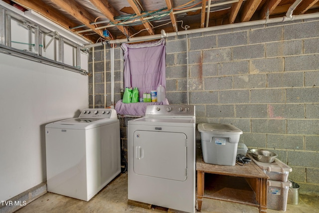 laundry room with concrete block wall, laundry area, and washing machine and dryer
