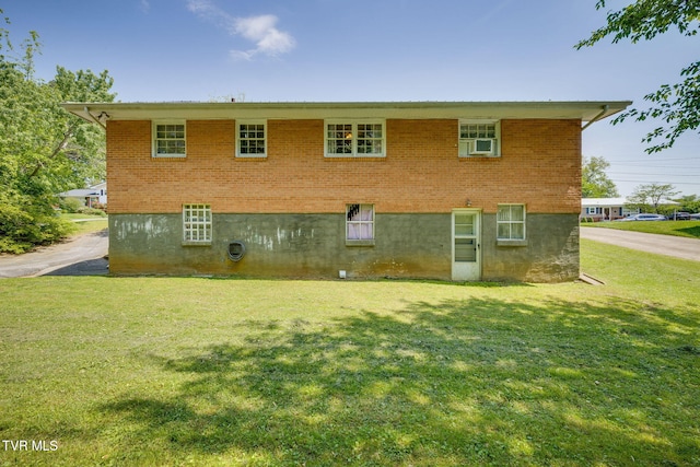 back of property with a lawn and brick siding