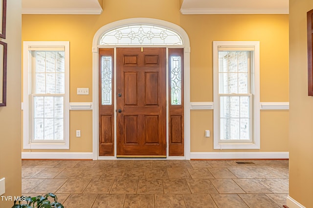 foyer entrance featuring visible vents, ornamental molding, and baseboards