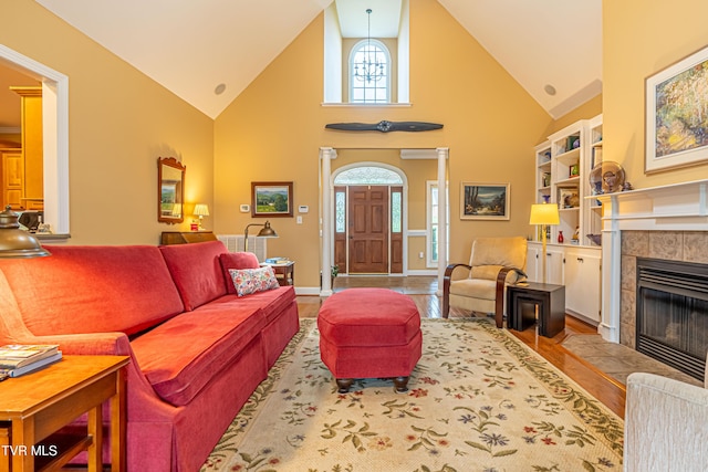 living room with high vaulted ceiling, baseboards, and a tile fireplace