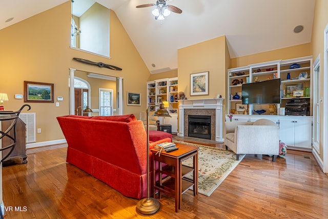 living room featuring a tiled fireplace, ceiling fan, hardwood / wood-style floors, and high vaulted ceiling