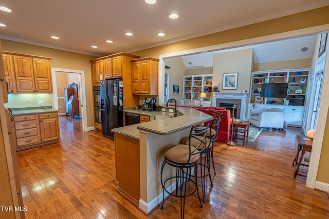 kitchen with crown molding, a peninsula, a sink, and black appliances