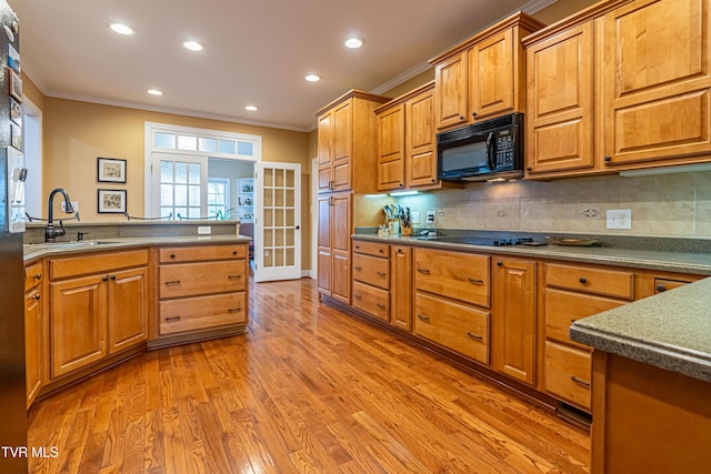 kitchen featuring crown molding, a sink, light wood-style flooring, and black appliances