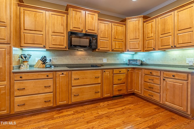 kitchen featuring light wood-style floors, ornamental molding, black appliances, and tasteful backsplash