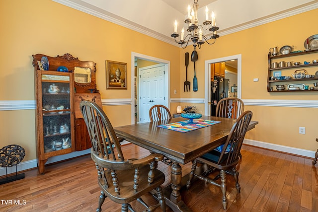 dining space featuring wood-type flooring, ornamental molding, baseboards, and a notable chandelier