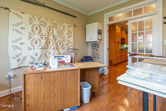 office space with crown molding, baseboards, and light wood-style flooring