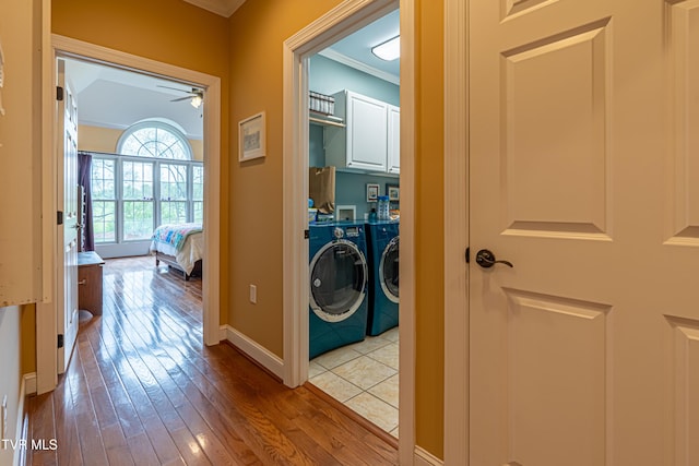 washroom featuring cabinet space, ornamental molding, hardwood / wood-style floors, a ceiling fan, and washing machine and dryer