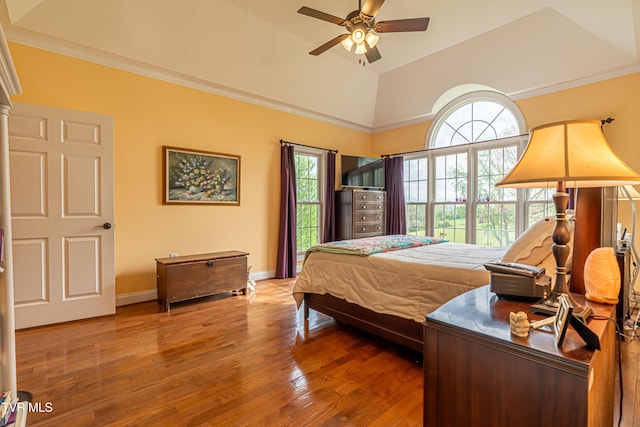 bedroom featuring baseboards, crown molding, wood finished floors, and vaulted ceiling