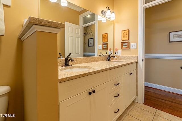 bathroom featuring double vanity, toilet, a sink, and tile patterned flooring
