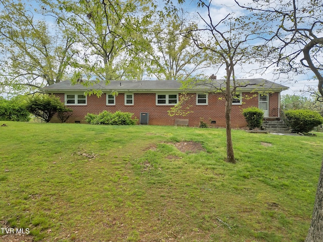 back of property featuring a lawn, brick siding, and crawl space