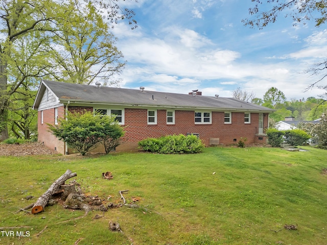 rear view of house with a yard, brick siding, and crawl space
