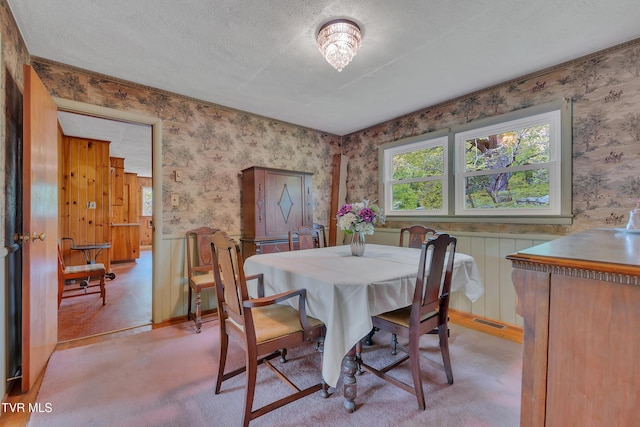 dining room featuring light carpet, wallpapered walls, and visible vents