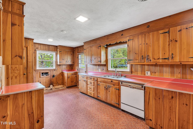 kitchen featuring white dishwasher, a textured ceiling, brown cabinetry, and a sink