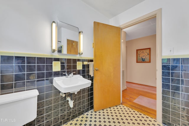 bathroom featuring visible vents, tile walls, a sink, a wainscoted wall, and toilet