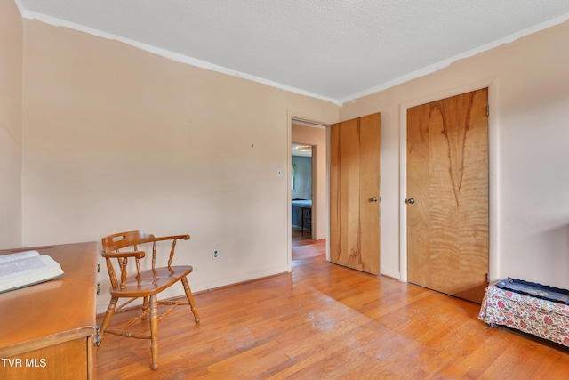 sitting room featuring crown molding, baseboards, and light wood-type flooring