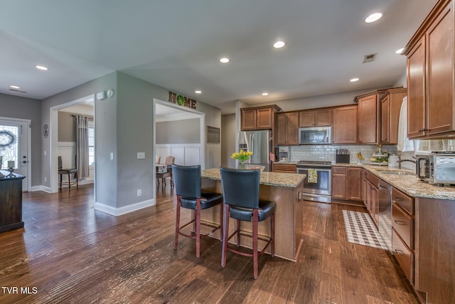kitchen featuring a kitchen island, backsplash, a sink, dark wood-style floors, and stainless steel appliances