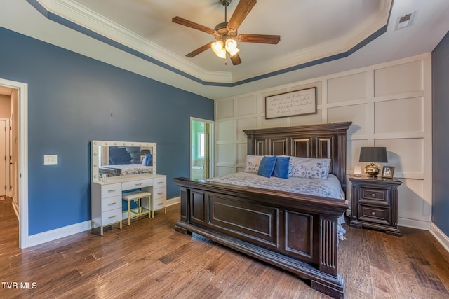 bedroom featuring ornamental molding, a tray ceiling, wood finished floors, and visible vents
