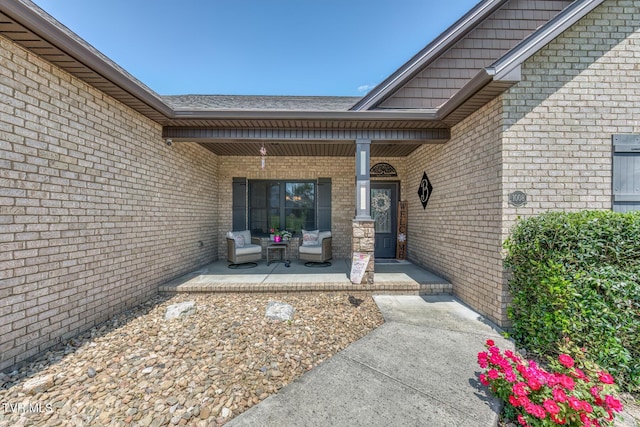 entrance to property with a porch and brick siding