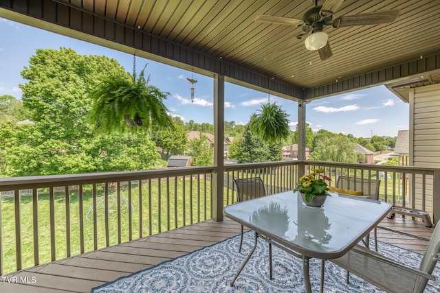 wooden terrace featuring a lawn, a ceiling fan, and outdoor dining area