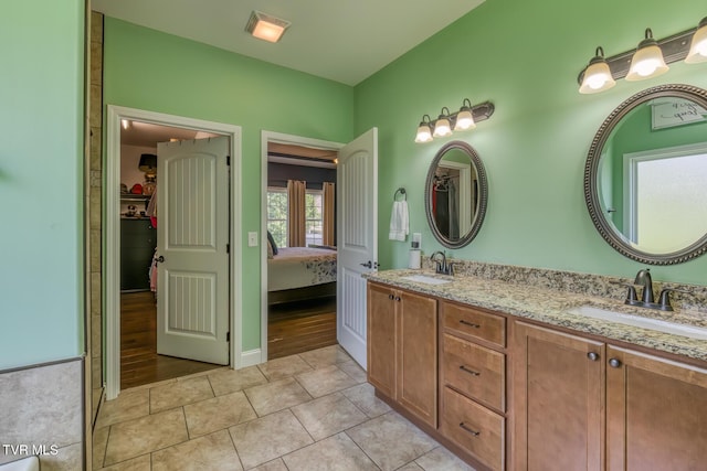 full bath with double vanity, tile patterned floors, a sink, and a walk in closet